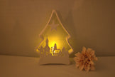 Witte kunststof kerstboom verlicht met warm geel LED waxinelichtje en winterdorp silhouet – sfeervolle kerstdecoratie

