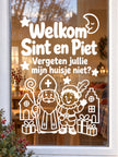 Witte raamsticker Welkom Sint en Piet met tekst 'Vergeten jullie mijn huisje niet?' op raam met sfeervolle kaarsen op achtergrond