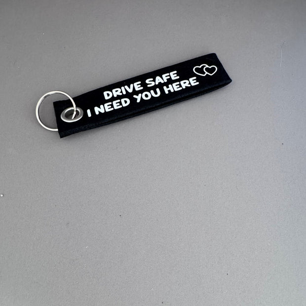 Zwarte viltsleutelhanger met witte tekst 'Drive Safe I Need You Here' – persoonlijk cadeau voor rijbewijs of nieuwe auto van Shop V-Ric
